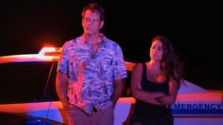 Vince Vaughn and Natalie Martinez lean against a cop car at night in the Apple TV Plus original, "Bad Monkey"