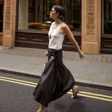 Alice Satterthwaite wears a white tank top, brown maxi skirt and flip flop heels: best bottoms to wear with flip-flop heels 2026 