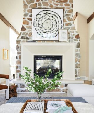 Large family living space with large brick chimney breast and framed fireplace, neutral color palette with black and white artwork on cream painted walls, leather lounge chair, white sofa