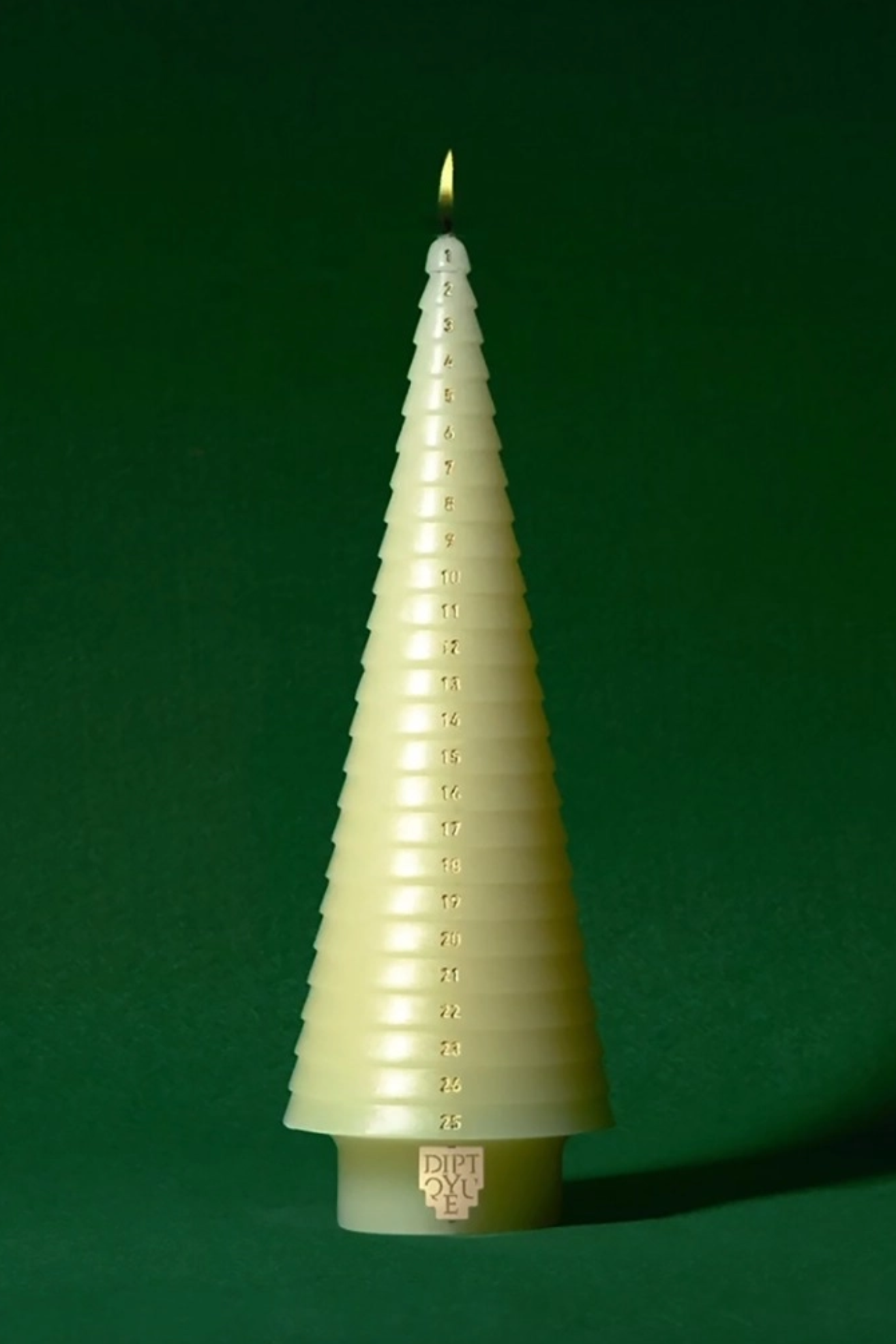 A white tree-shaped advent candle with gold etchings