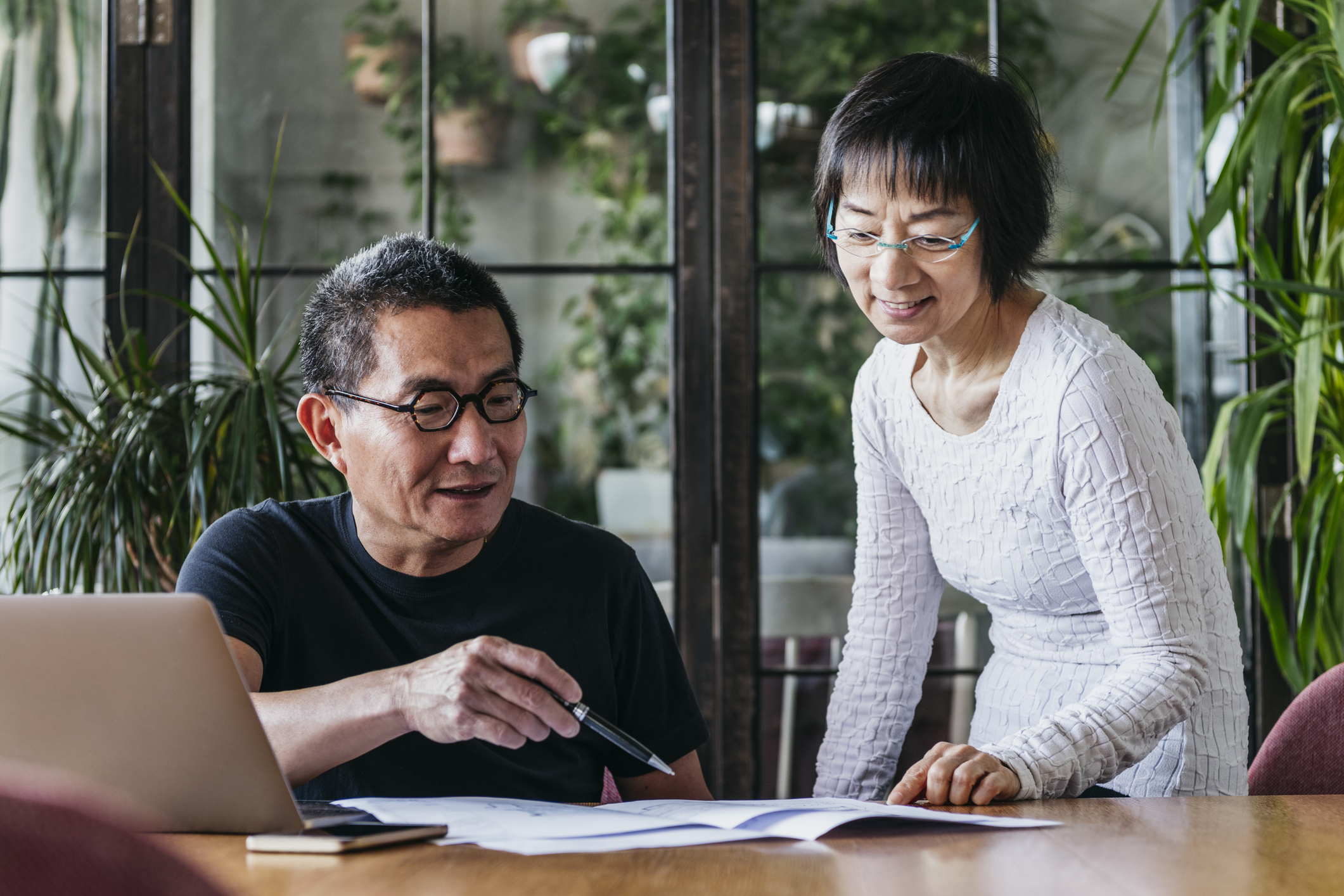 A senior couple reviews finances at dining table.