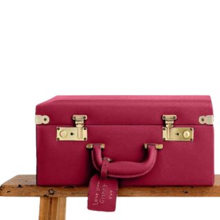A berry colored suitcase on a wooden bench