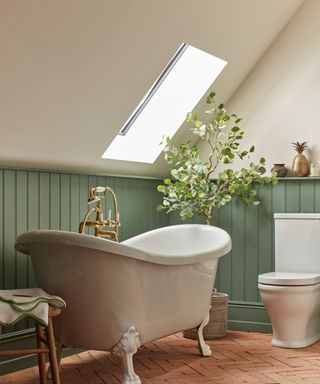 small loft bathroom with freestanding rolltop bath and rooflight and green half wall panelling