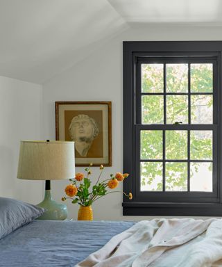 A bedroom with a black-framed window and a lamp