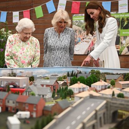 st austell, england june 11 queen elizabeth ii l, camilla, duchess of cornwall c and catherine, duchess of cambridge r look at a scale model of big lunch events that have been held over the years during an event in celebration of the big lunch initiative at the eden project during the g7 summit on june 11, 2021 in st austell, cornwall, england uk prime minister, boris johnson, hosts leaders from the usa, japan, germany, france, italy and canada at the g7 summit this year the uk has invited india, south africa, and south korea to attend the leaders' summit as guest countries as well as the eu photo by oli scarff wpa pool getty images