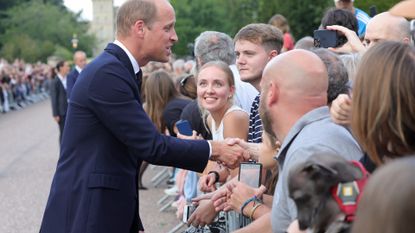 Prince William, Prince of Wales shakes hands with members of the public on the Long walk at Windsor Castle on September 10, 2022 in Windsor, England. Crowds have gathered and tributes left at the gates of Windsor Castle to Queen Elizabeth II, who died at Balmoral Castle on 8 September, 2022.
