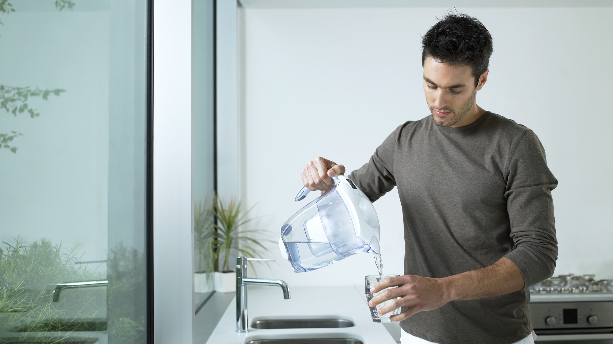 Man pouring water from filter jug into glass