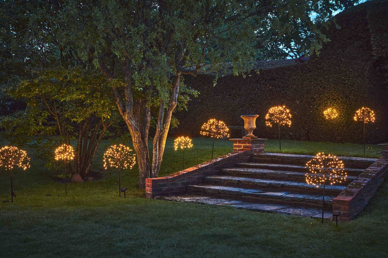 A garden with small solar lights planted across the lawn