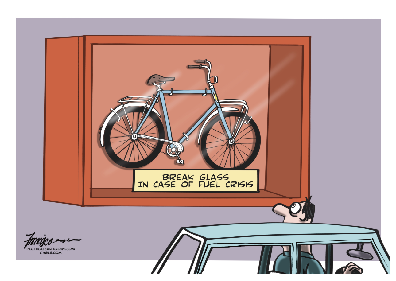 A man in a car looks at a bicycle encased in glass. A sign on the glass reads, "Break glass in case of fuel crisis."