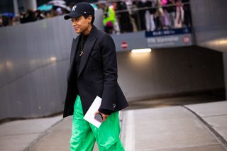 Tamu Mcpherson in baseball hat, blazer, and green pants.