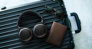 Audio-Technica headphones in muted lighting, worn by a man while gaming and also on a briefcase