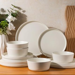 A set of white dinner plates and bowls with high rim edges