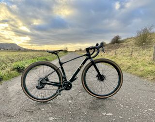 The Liv Devote Advanced Pro in a shiny black in the middle of a bleak gravel road