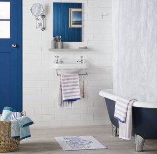 Coastal style bathroom with striped towels and blue bath tub