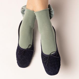 Woman wearing navy woven Eledera ballet flats with pistachio colored socks.