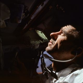 Walter Cunningham looks out of the window of the Apollo command module in Earth orbit.