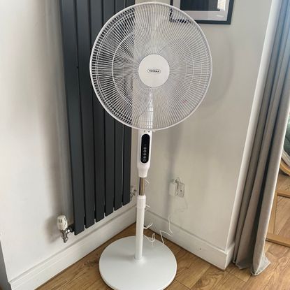 Vonhaus 16'' pedestal fan at mid-height in a corner of a room next to a dark grey vertical radiator