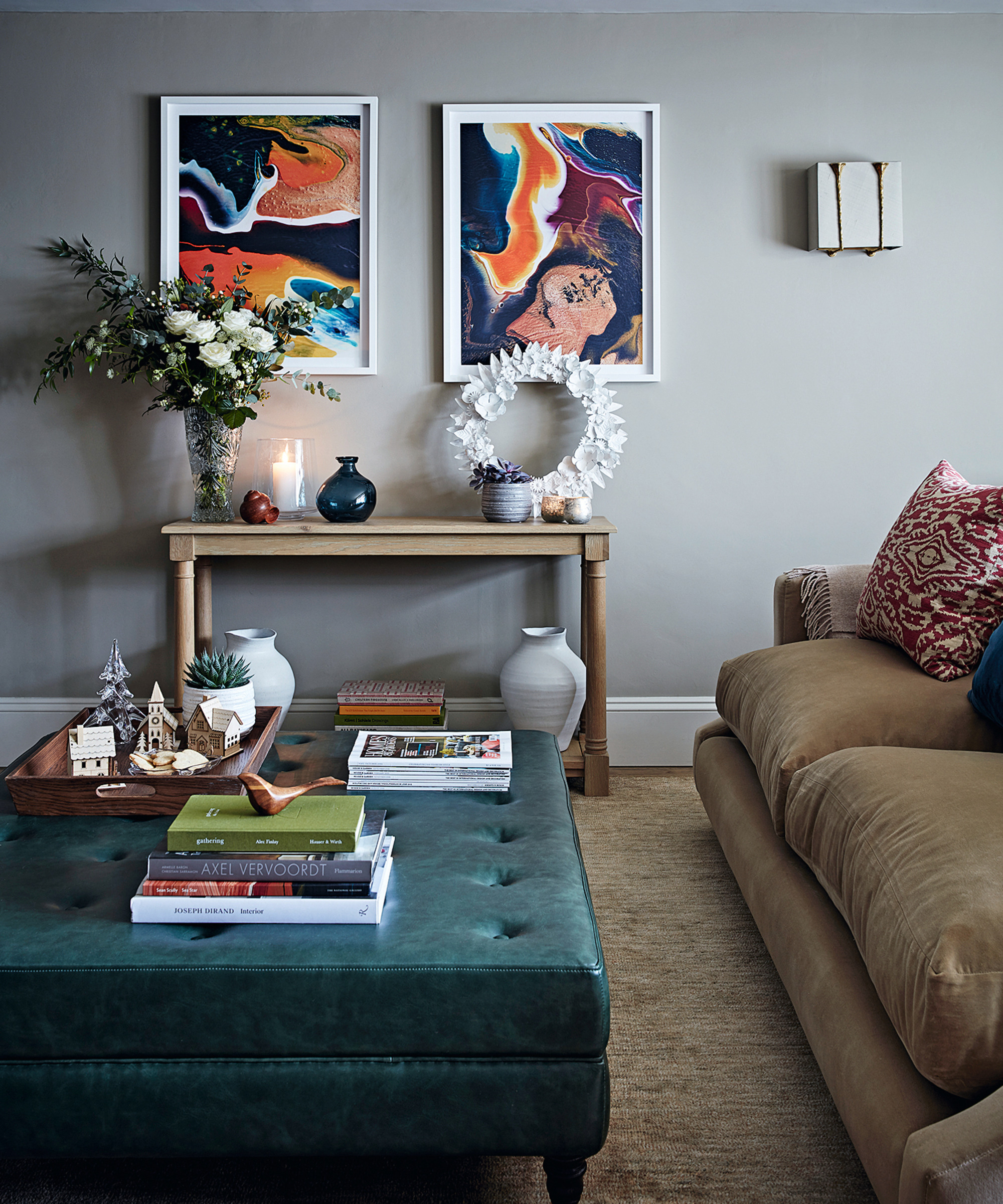 console table with vase of flowers, white wreath and two artworks above in a sitting room