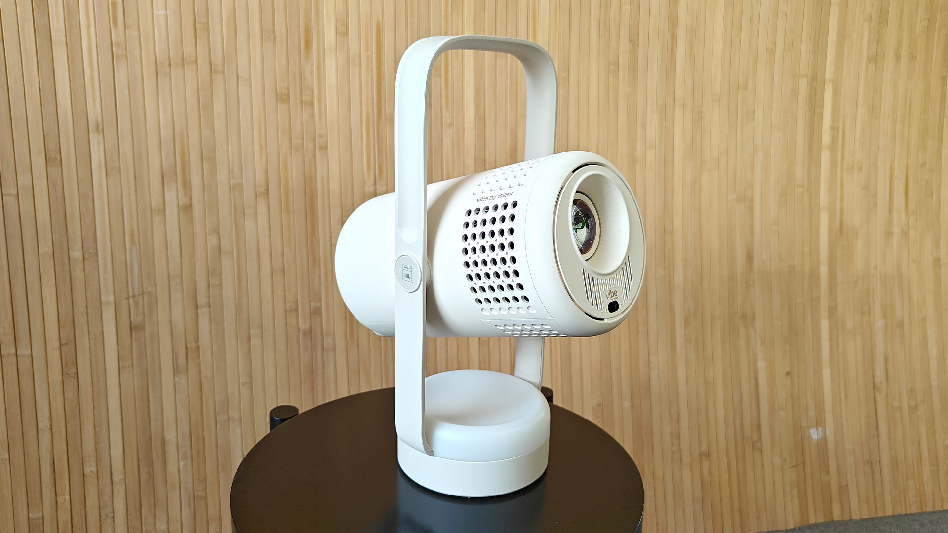 Xgimi Vibe One portable projector on small black table against bamboo effect wall
