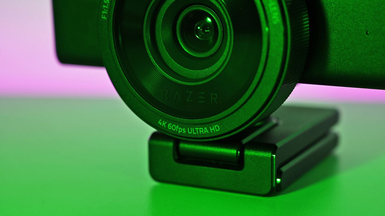 Close-up of the Razer Kiyo V2 Pro webcam lens showing "4K 60fps ULTRA HD" and "RAZER" branding in green lighting.