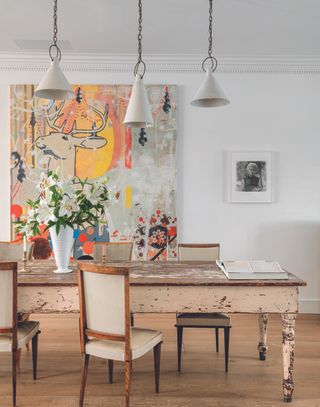 A dining room with a wooden table and a large artwork