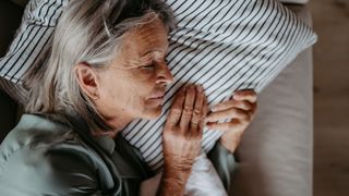 An older woman lies in bed asleep