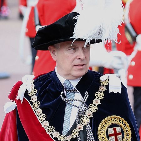 Prince Andrew attending Garter Day wearing long ceremonial robes and a black hat with a large white feather protruding from the top and a red sash and a gold chain