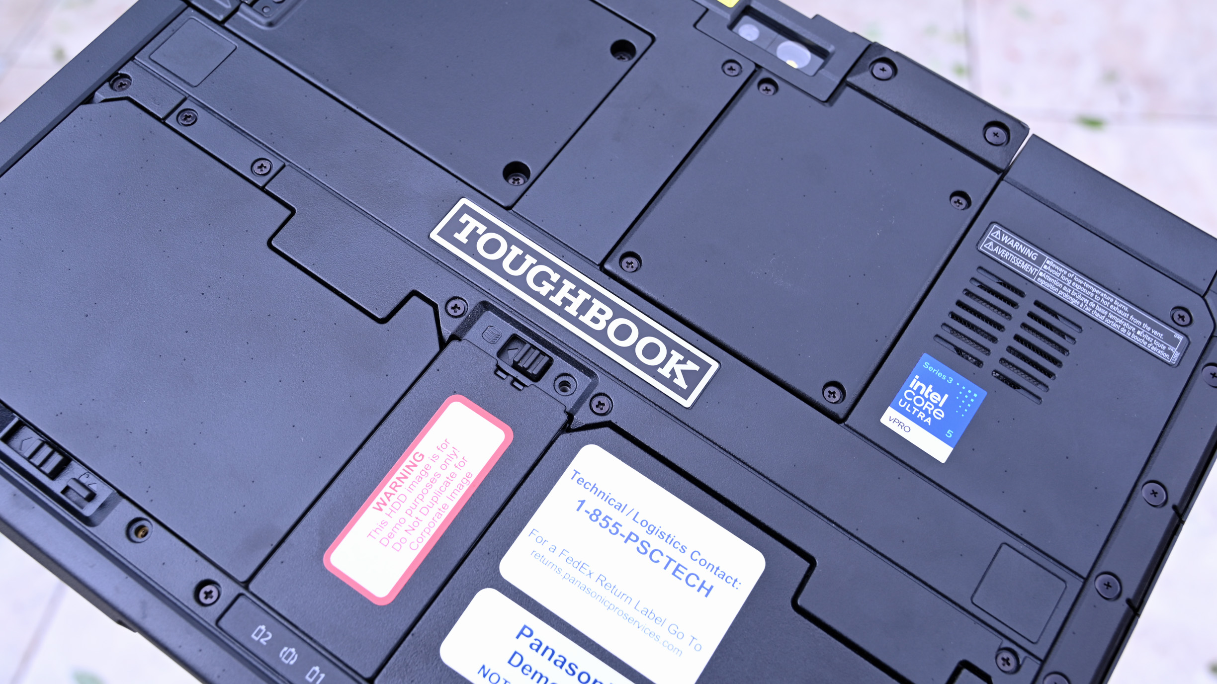 Rear chassis of a Panasonic TOUGHBOOK 34 displaying modular latches, TOUGHBOOK logo, and Intel Core Ultra 5 sticker.