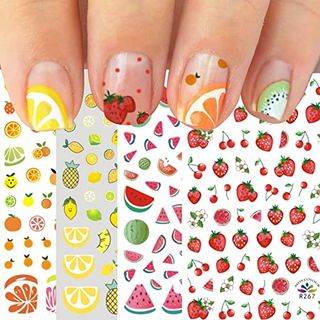 sheets of fruit nail stickers overlapping with fingers displaying the stickers on top