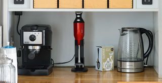 A kitchen counter with a kettle, hand blender and coffee machine