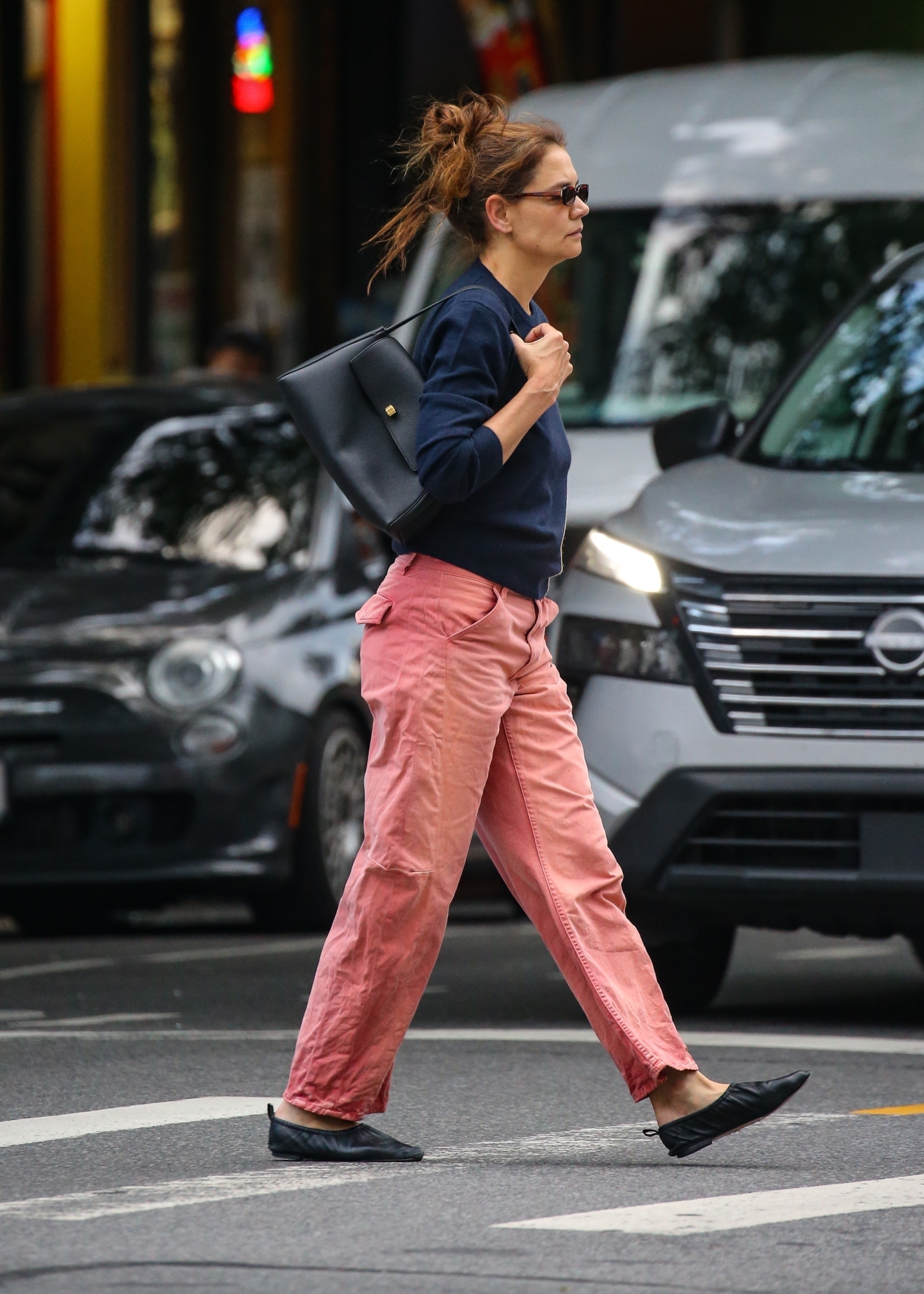Katie Holmes carries a black Khaite bag and wears a navy sweatshirt featuring the words Happy hours