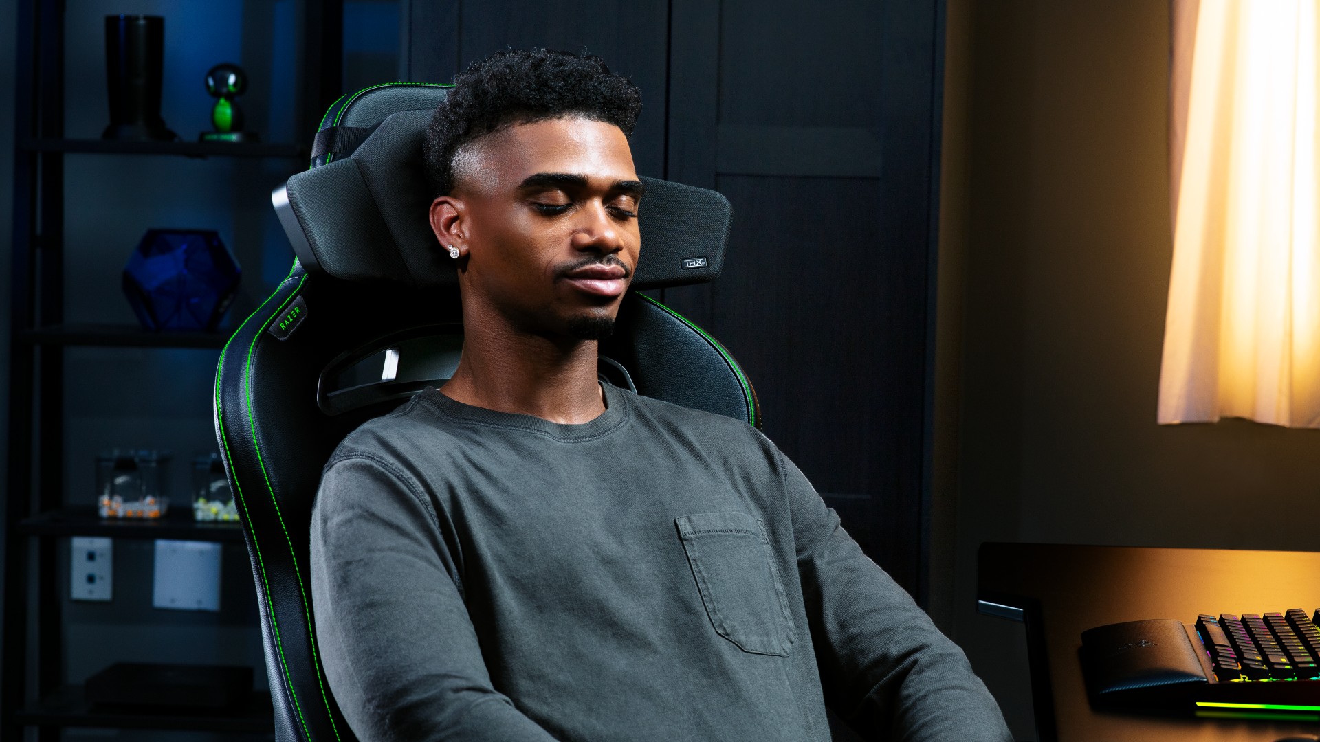 A person sitting in a Razer gaming chair relaxing with his head against the Razer Clio headrest speaker system