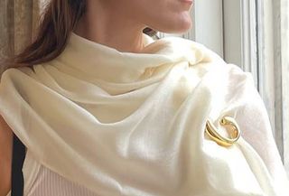 Editor Anna LaPlaca wearing white scarf, gold brooch, and white pillbox hat.