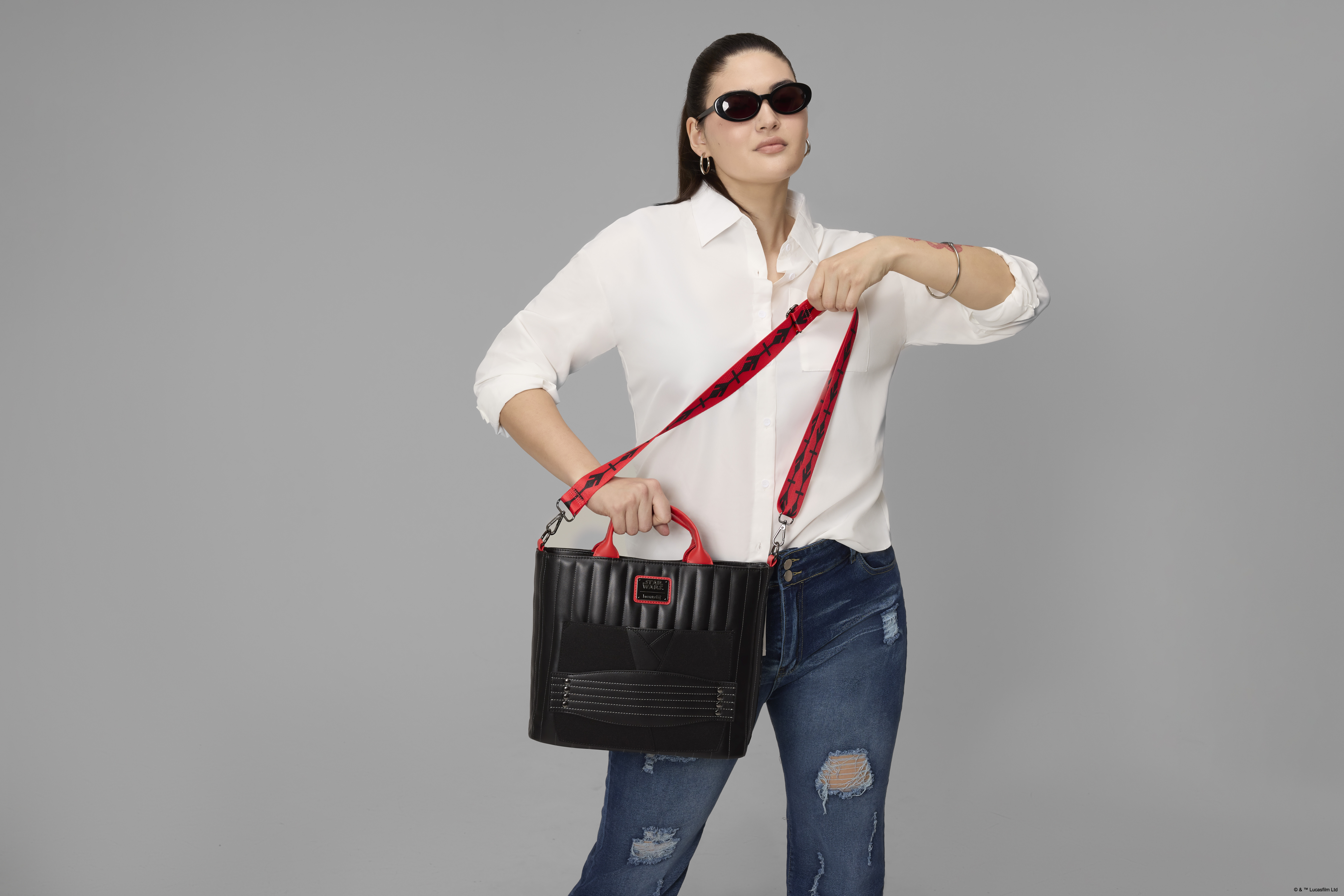 A woman holds the Loungefly Darth Maul bag in a gray environment