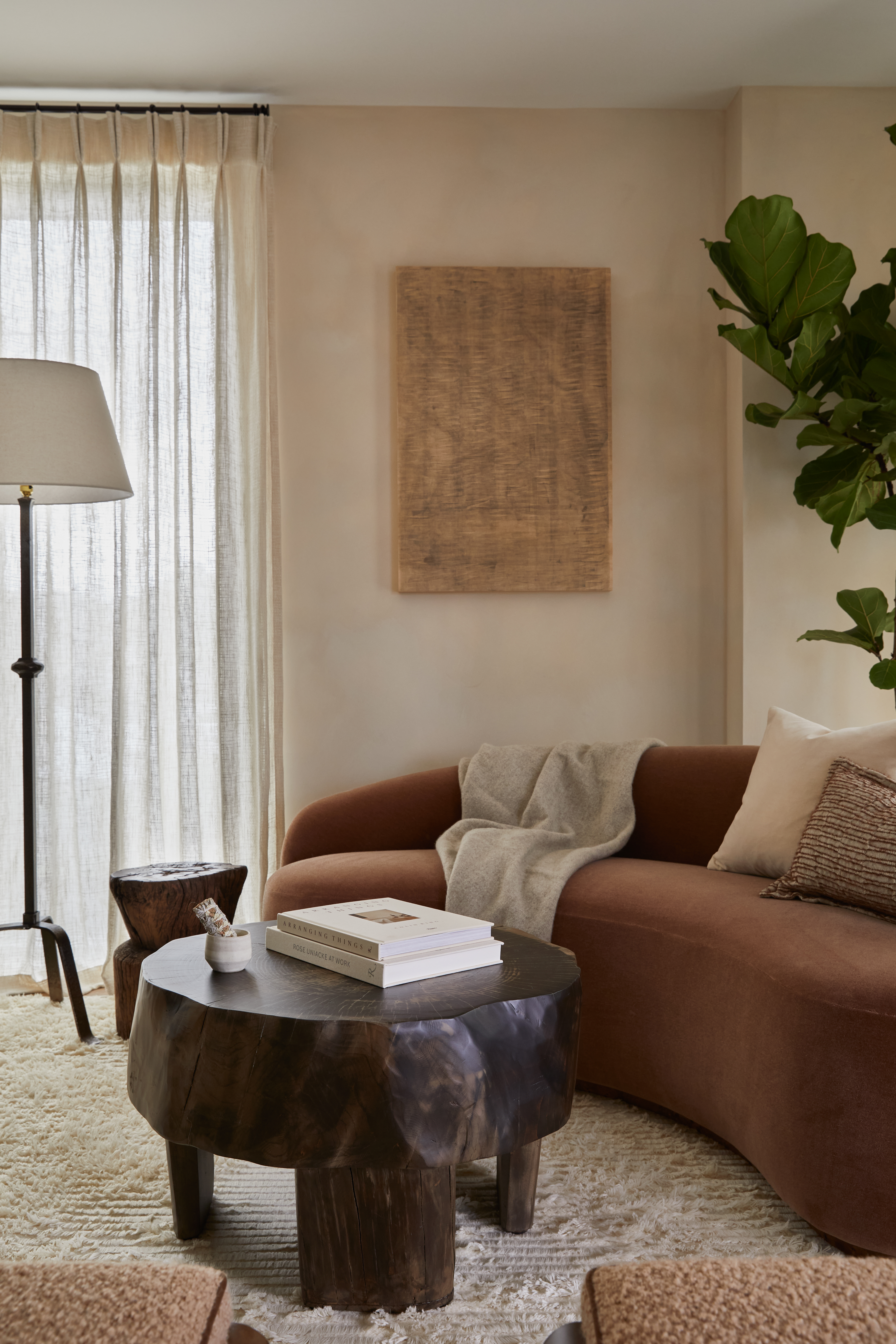 warm, earthy toned living room with a curved rust sofa and plaster finish walls