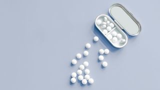 Melatonin tablets in pill case and spilling out onto a flat surface