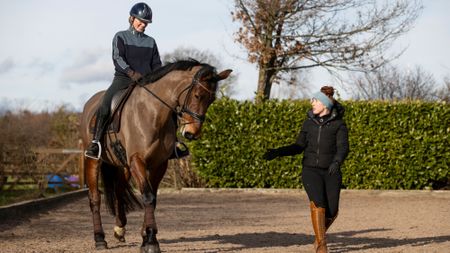 Becky Moody on the ground teaching a pupil riding a horse on a circle