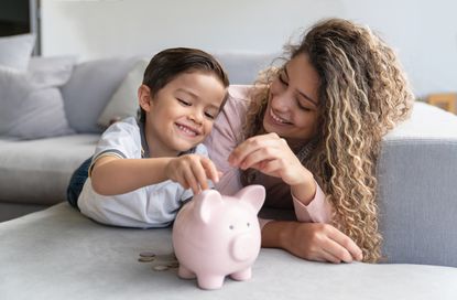 Mother and young son putting coins into a piggy bank