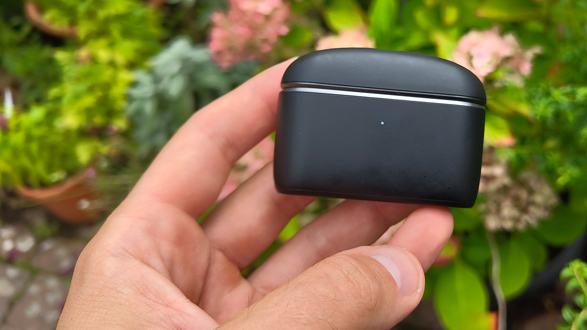 Sennheiser Momentum True Wireless 5 wireless earbuds case held in hand in garden