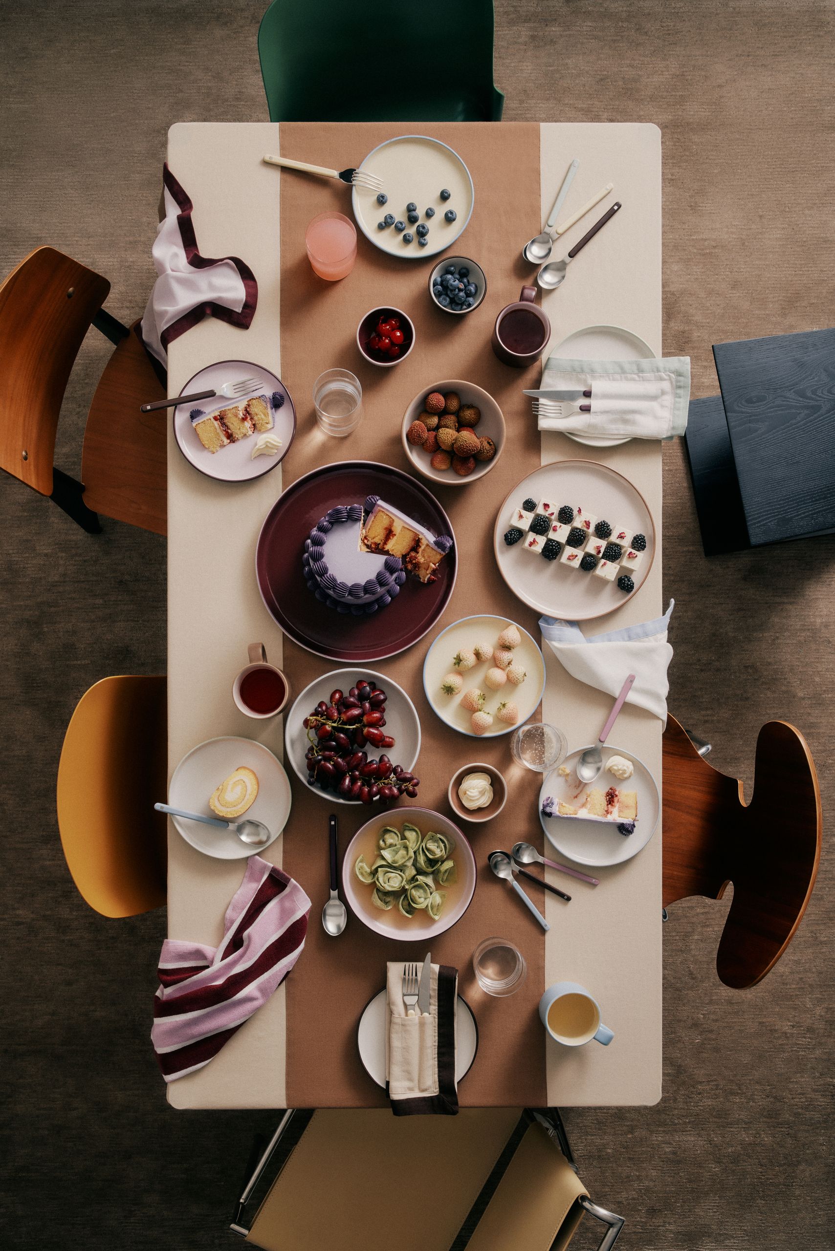 Image of a fashionable tablescape viewed from above with mismatched chairs around it. There is a brown, white, and purple color palette.