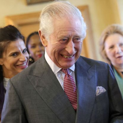 King Charles wearing a gray suit and laughing