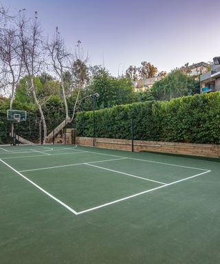 green tennis court with small red wall