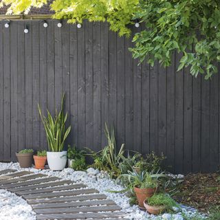 garden area with grey fence and white stone pathway