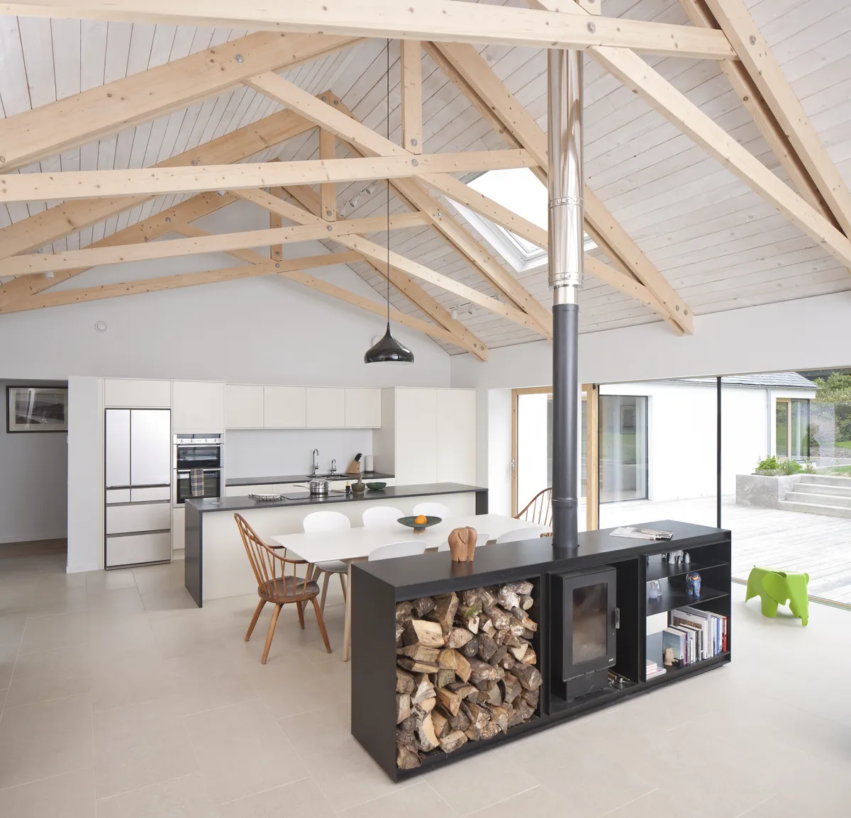 A double sided log burner in a built in storage sectional separating an open plan space in a barn conversion