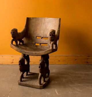 a wooden african chair on an orange backdrop