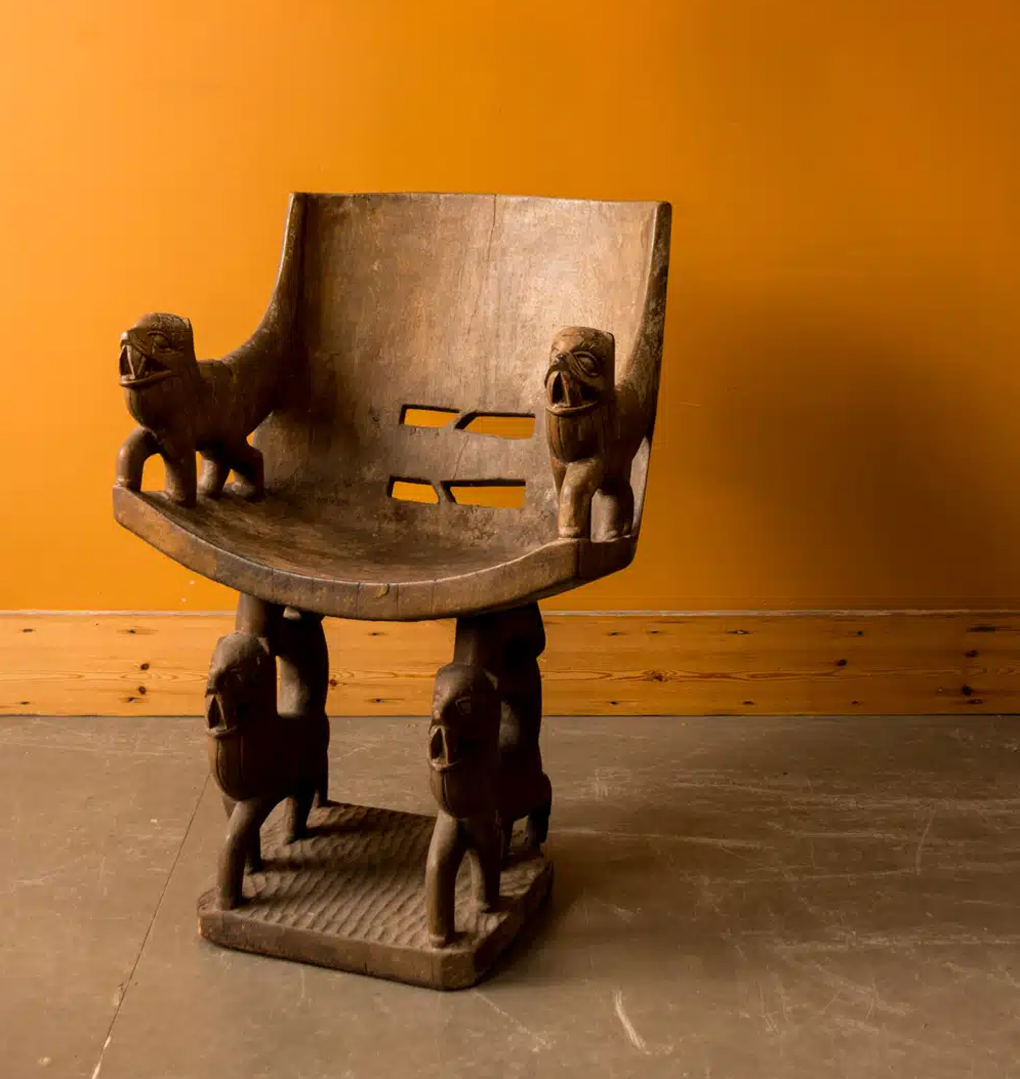 a wooden african chair on an orange backdrop