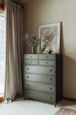 A cabinet with a vase and painting atop it