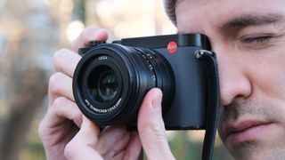 A Leica Q3 43 camera held up to a persons face