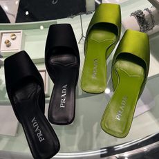 Black and green pairs of Prada square-toe kitten heel mules.