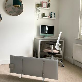 White AENO panel heater in a white home office, with cream carpets, a white desk, and shelves above it